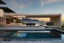 a pool with a large deck and a large building with a view of the mountains